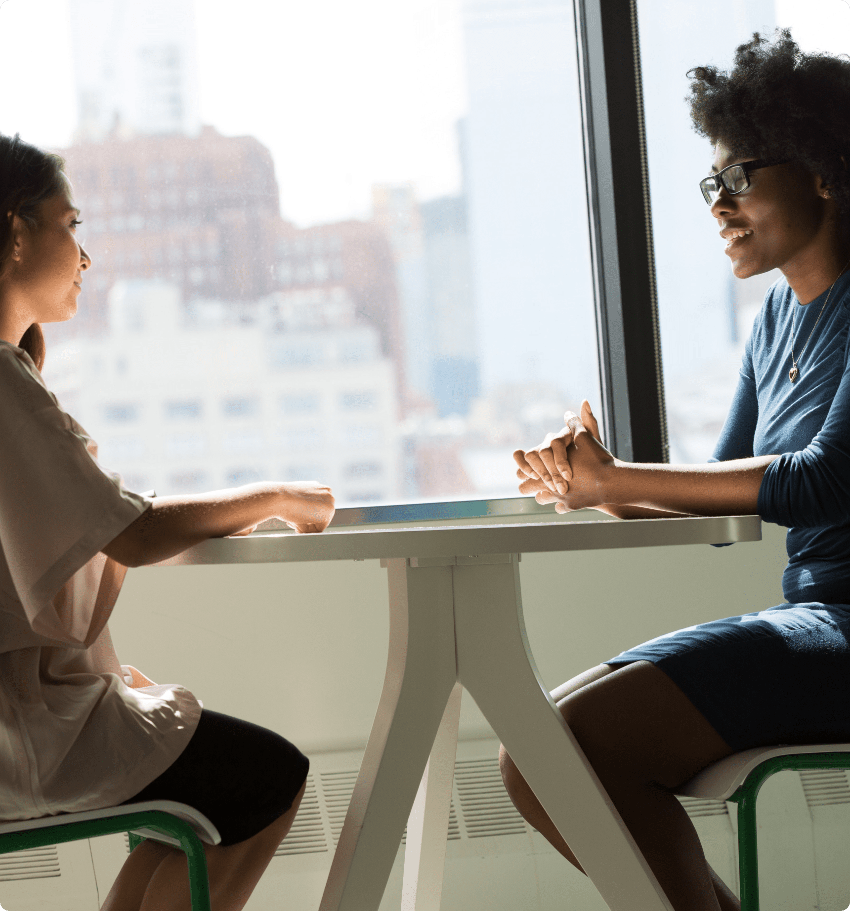 Dos mujeres hablando en una pequeña mesa redonda en un edificio de oficinas