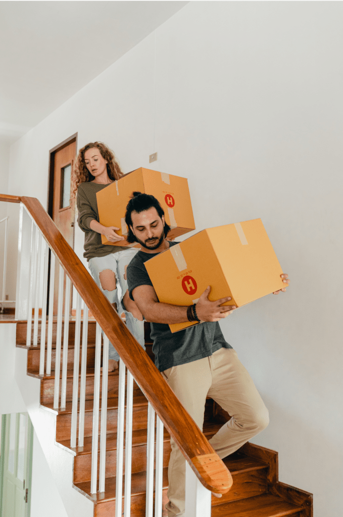 Hombre y mujer cargando cajas de mudanza por las escaleras.