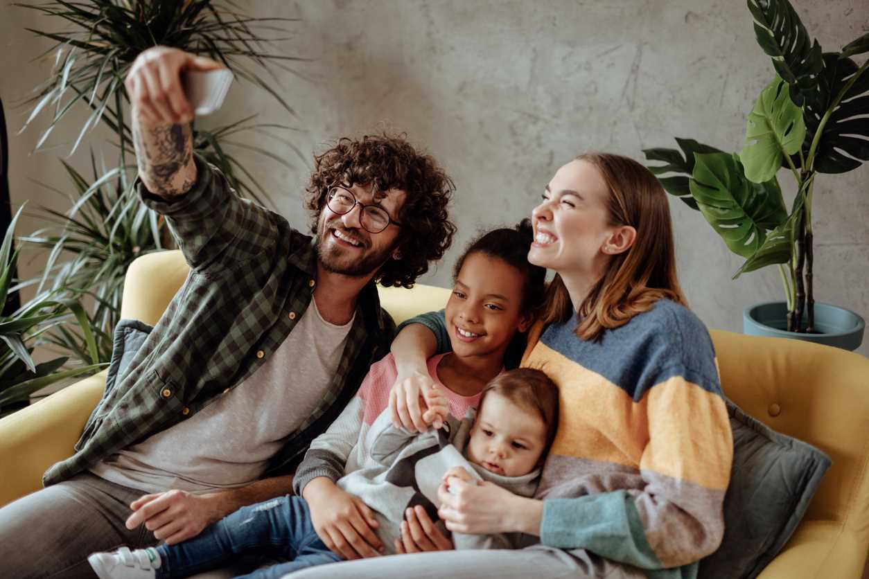 Family with an adopted child taking a photo while sitting on sofa