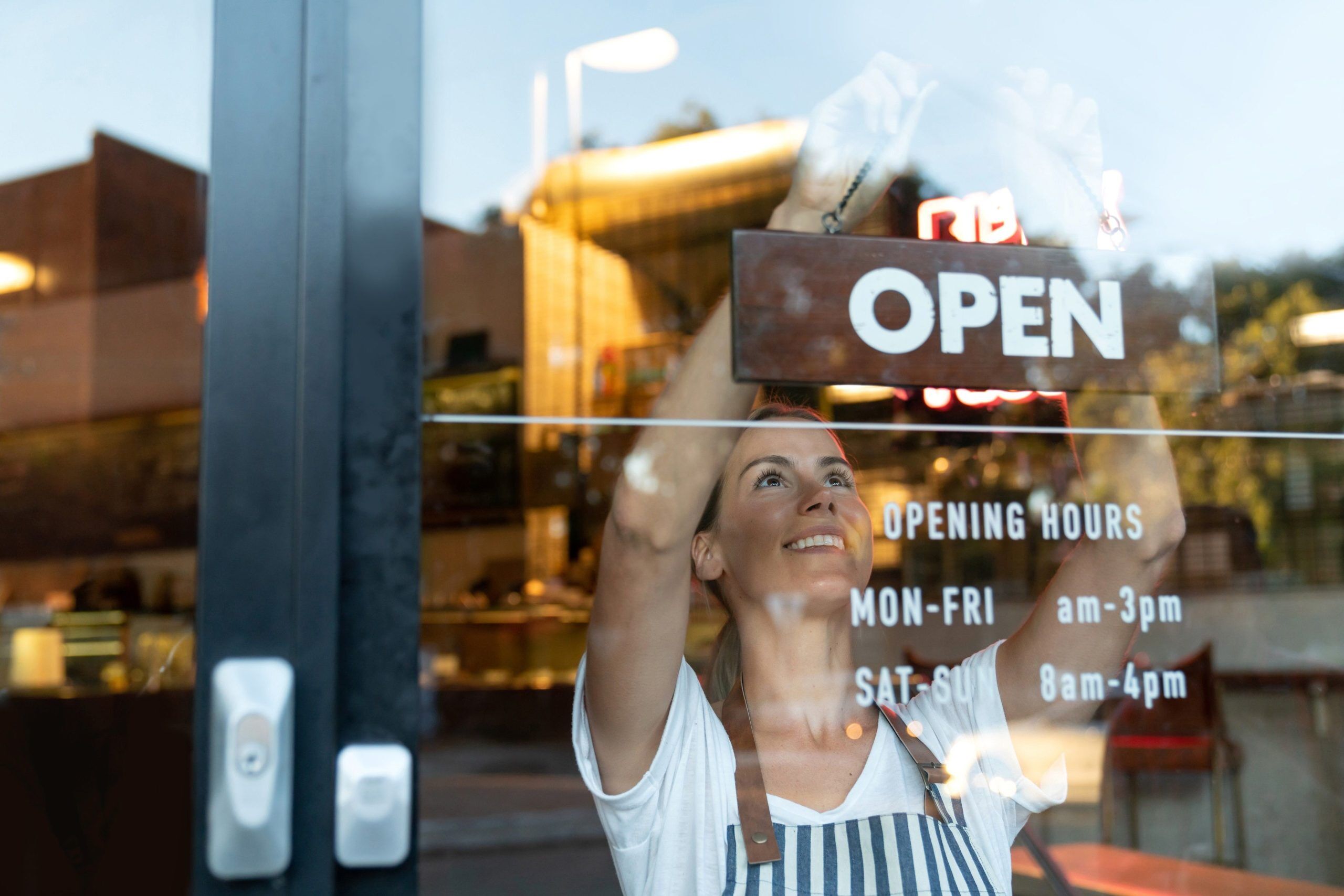 Small business owner placing Open sign on shop door