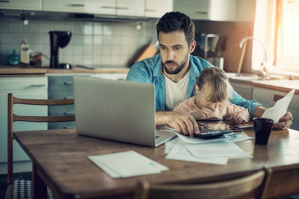 Father holding child working at kitchen table
