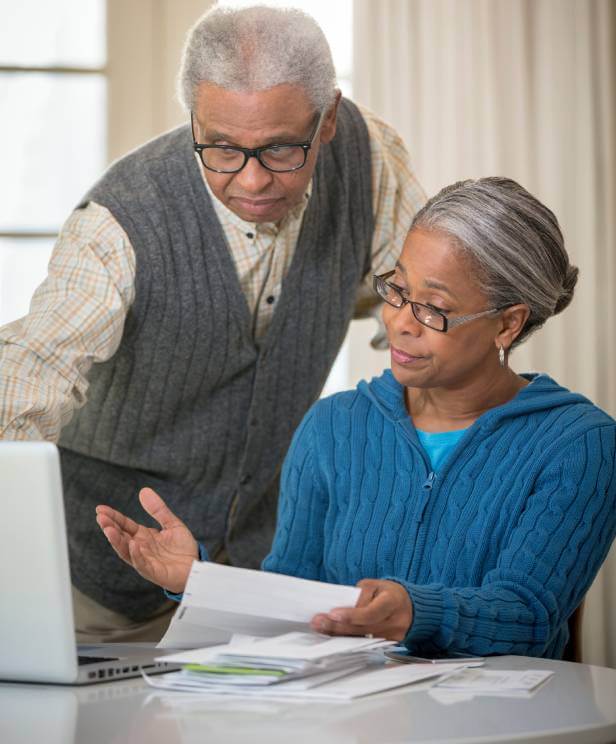 Elderly couple looking at documents and laptop computer concerned abou t what is a lien on a house.