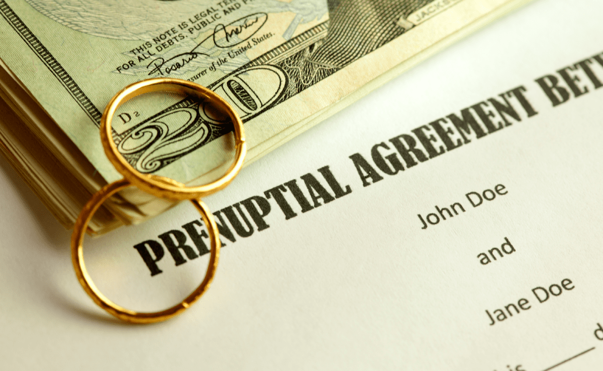 Prenuptial Agreement document with wedding rings & money nearby