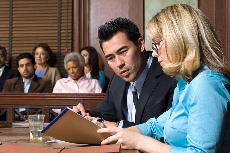 Lawyer and client talking in a courtroom.