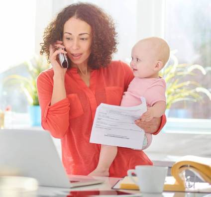 Mother holding a baby while talking on the phone about a daycare contract.