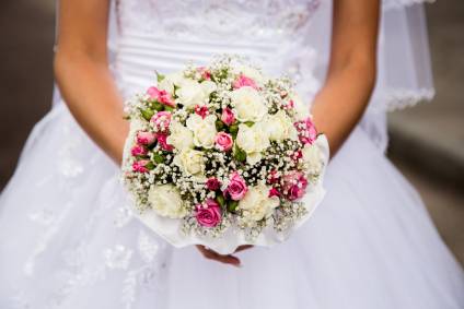 Bride in wedding dress holding a bridal flowers.