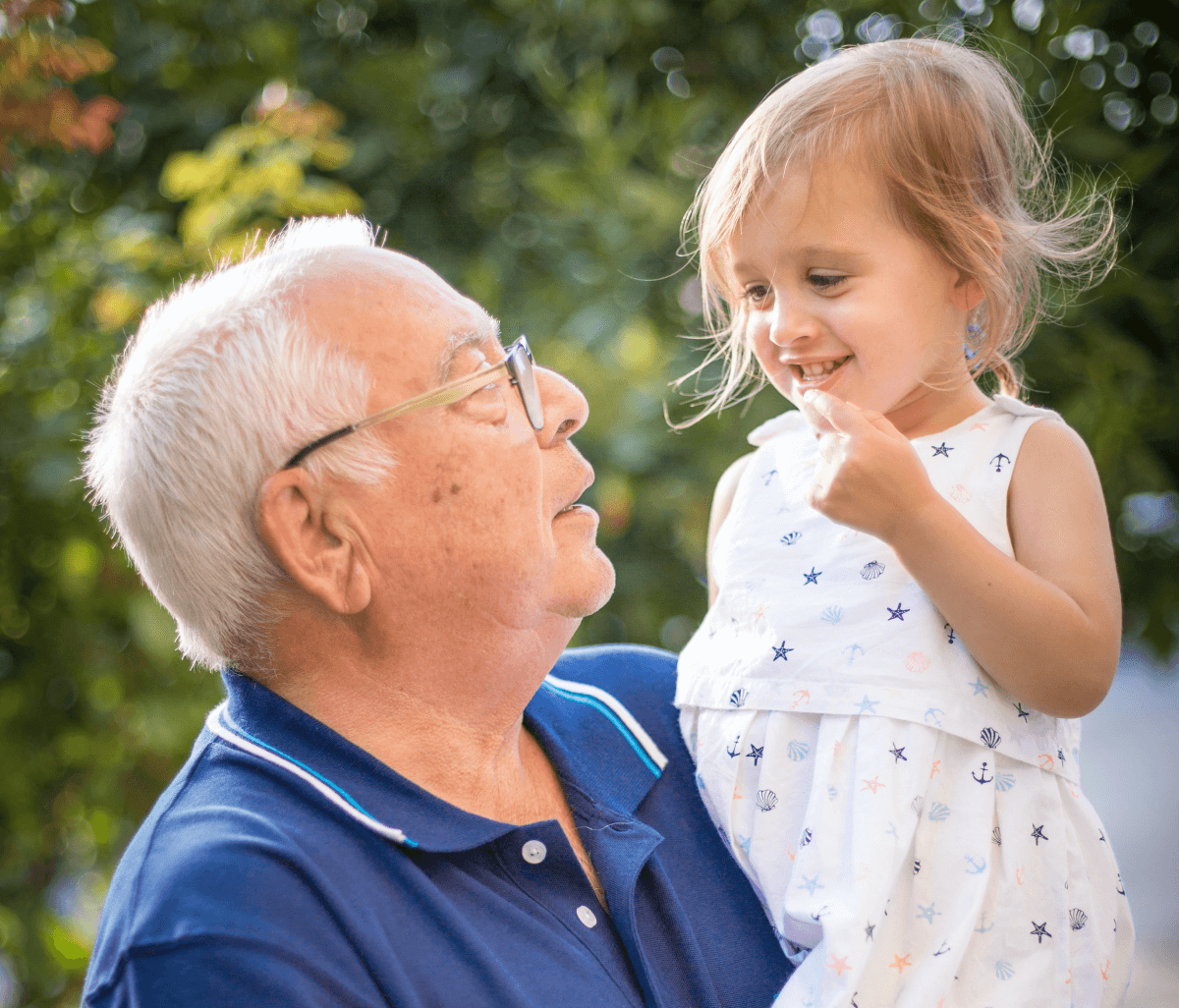 Abuelo sosteniendo a su joven nieta afuera