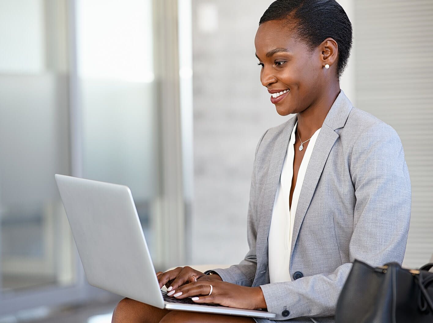 Mujer de negocios sonriente escribiendo en una computadora portátil.