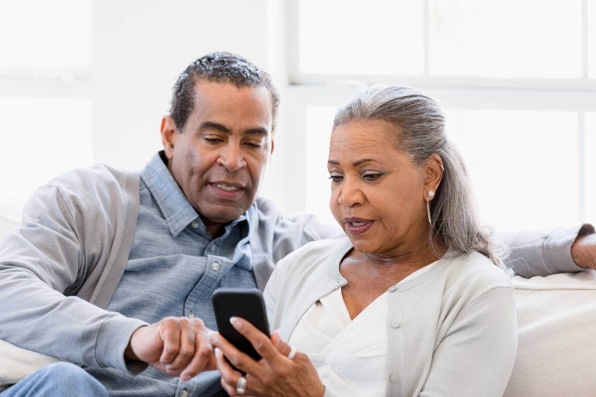 Couple looking at phone as they discuss retirement.