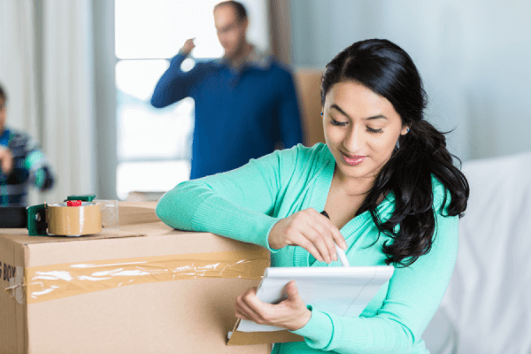 Mujer comprobando los elementos de la lista de comprobación de la mudanza de su apartamento