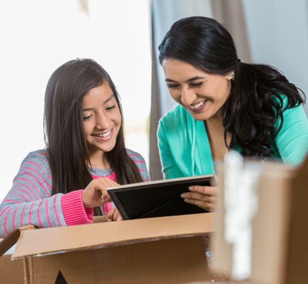 Madre e hija admiran una foto enmarcada que están metiendo en una caja de mudanza.