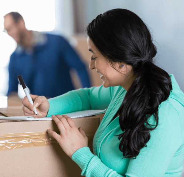 Mujer trabajando en la lista de comprobación de su mudanza.