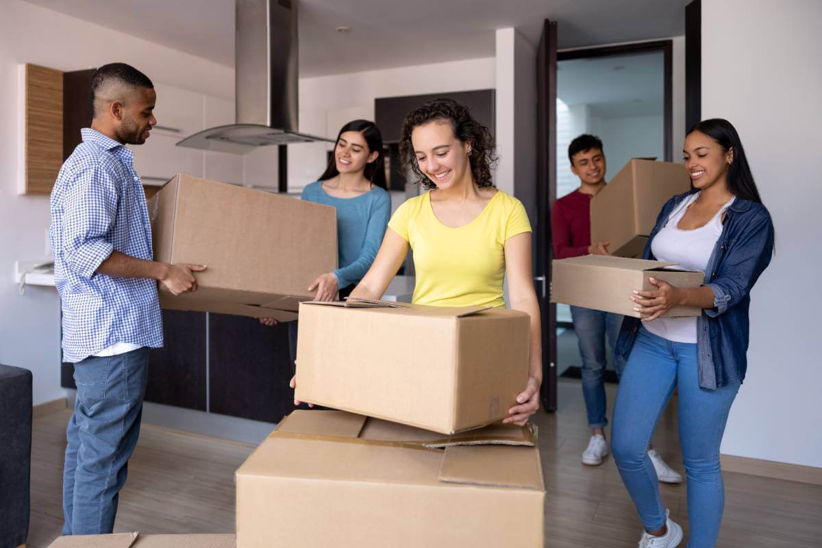 5 college student moving boxes into their rented apartment.