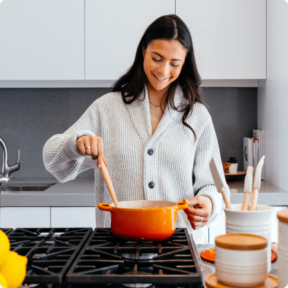 Una mujer remueve una olla en una cocina.