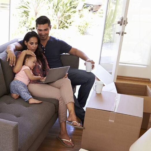 Familia de tres relajándose en el sofá mientras ven un portátil.