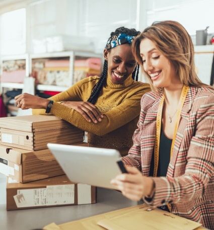 Empleados sonrientes de una pequeña empresa mirando la pantalla de un portátil.