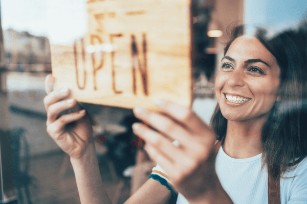 Mujer sonriente abriendo su tienda.  