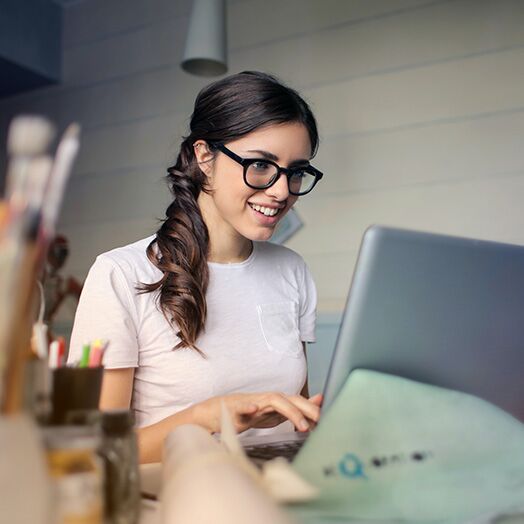 Joven sonriente escribiendo en un ordenador portátil en un escritorio.