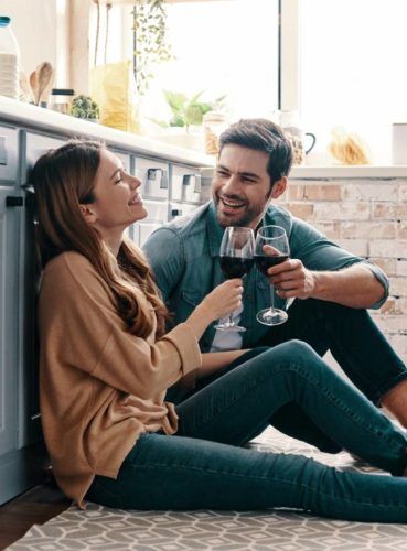 Hombre y mujer sentados en el suelo y bebiendo vino.