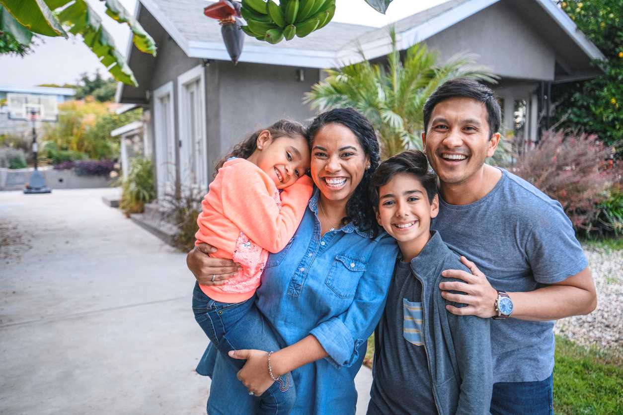 Familia feliz fuera de su nuevo hogar