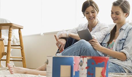 Mother & daughter looking at tablet while taking a break from painting a room