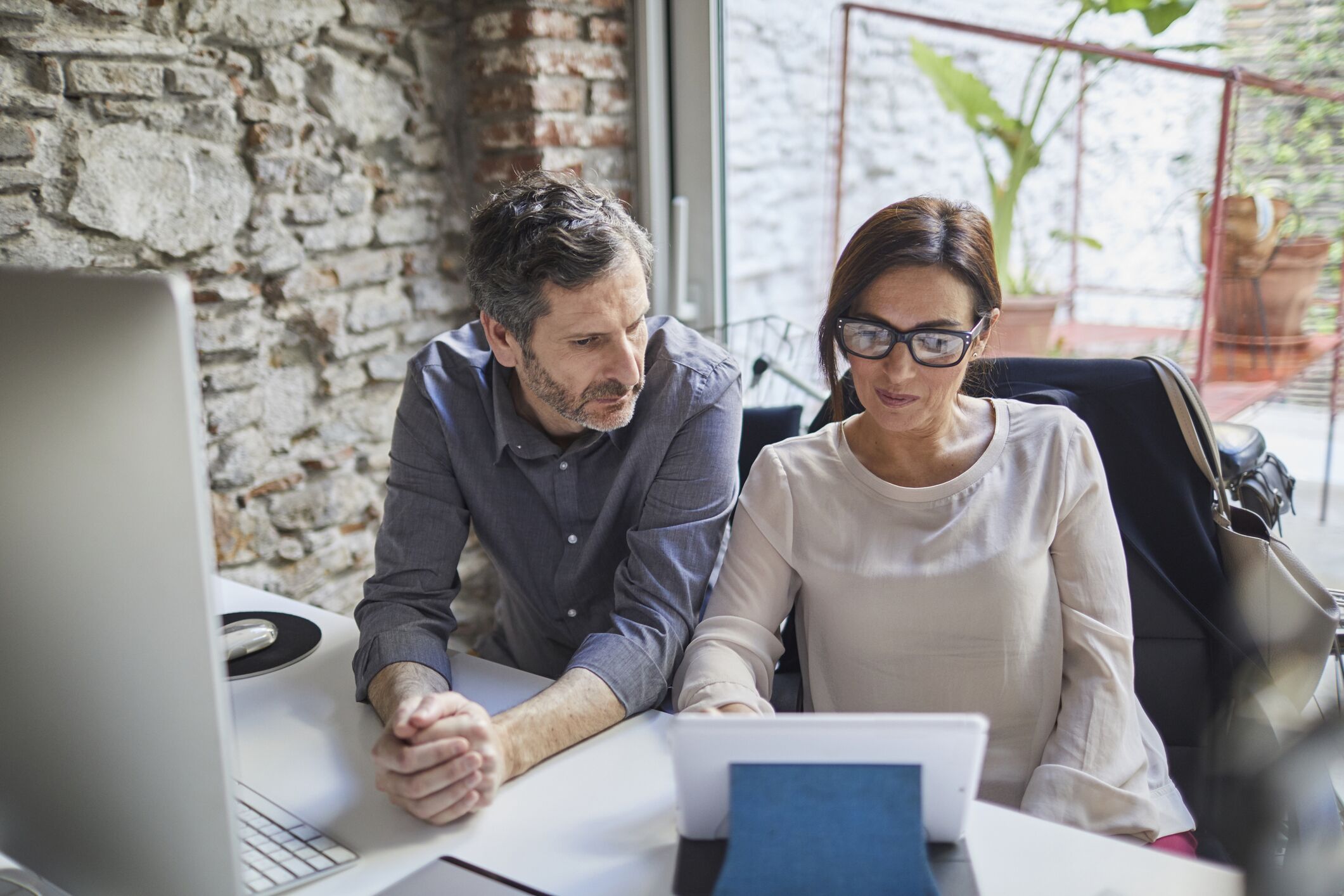 Middle-aged couple looking at debt documents on tablet