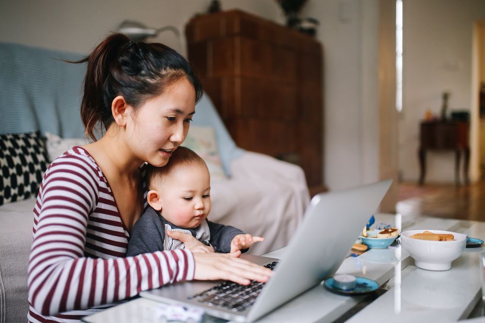 Joven madre trabajando desde casa con un bebé en su regazo