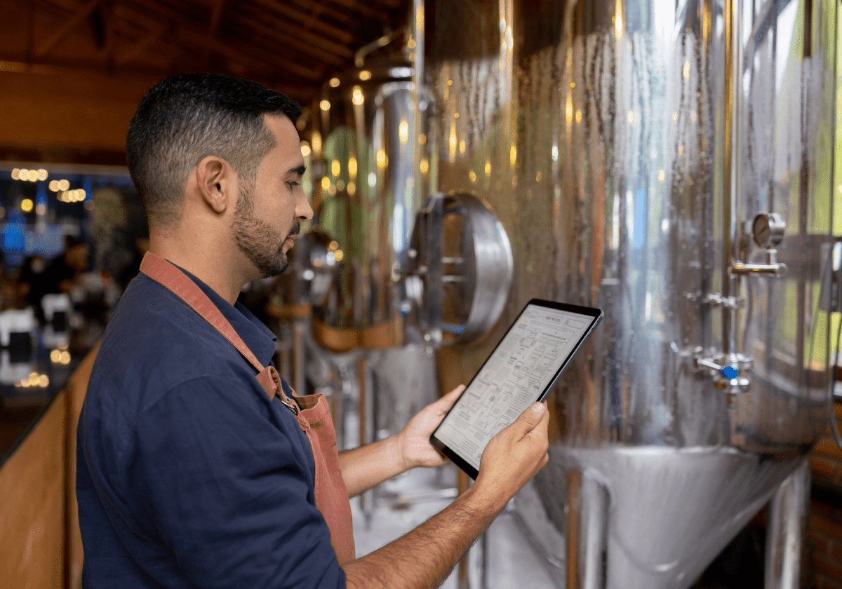 Brewery small business owner monitoring fermentation vessels, or FVs, by using a computer tablet