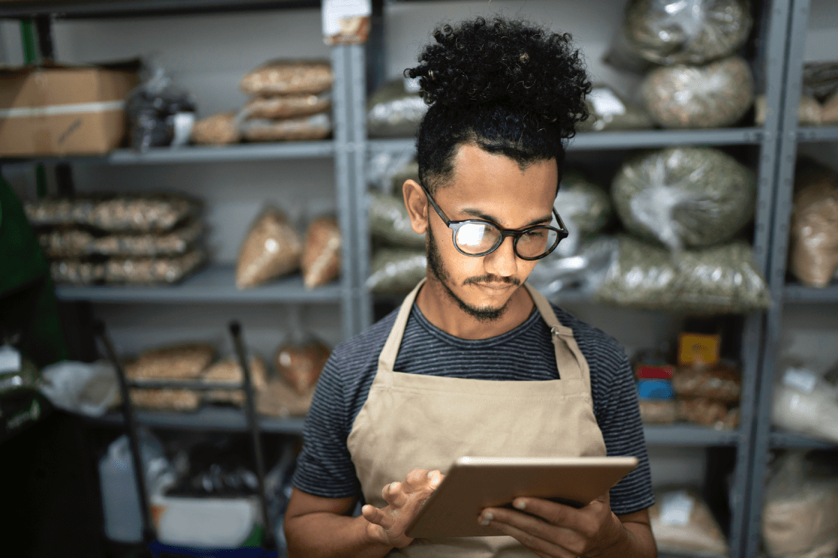 Small business owner using laptop in food storage room