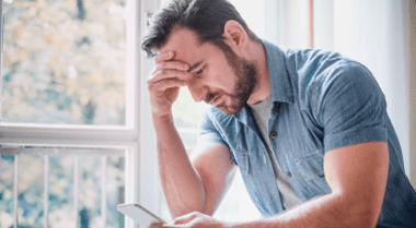 Worried man looking at his smartphone.