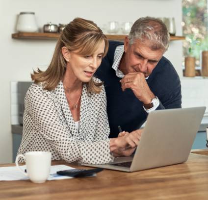 Couple discussing estate planning tips as they view a laptop computer in their kitchen.