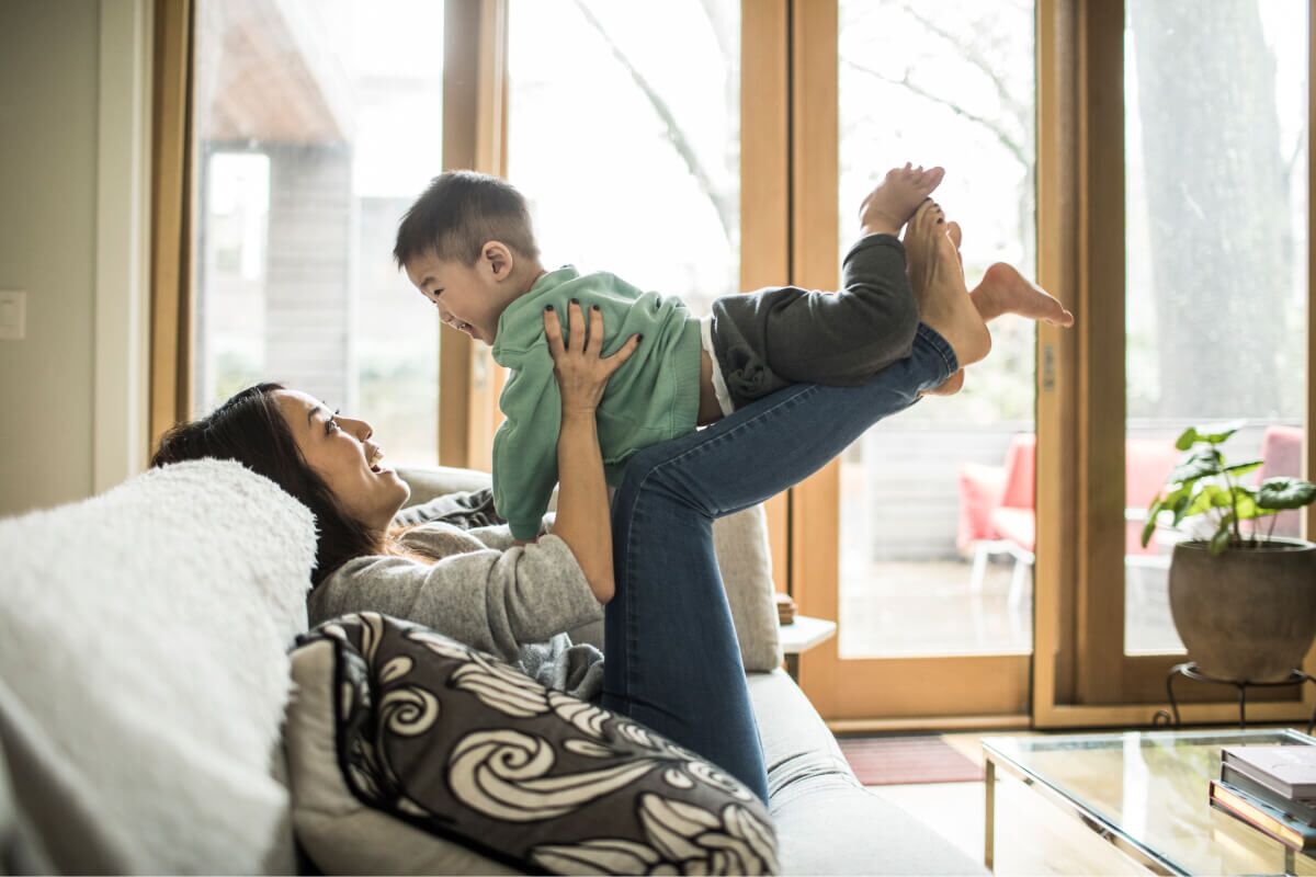 Mom laughing and playing with son on the couch