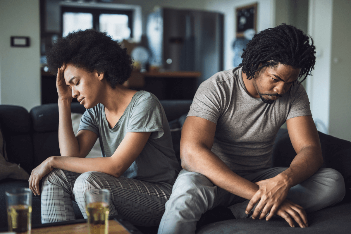 A sad man and woman sitting on a couch.