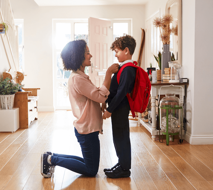 A mother fixing her young son's school uniform as he gets ready for school.