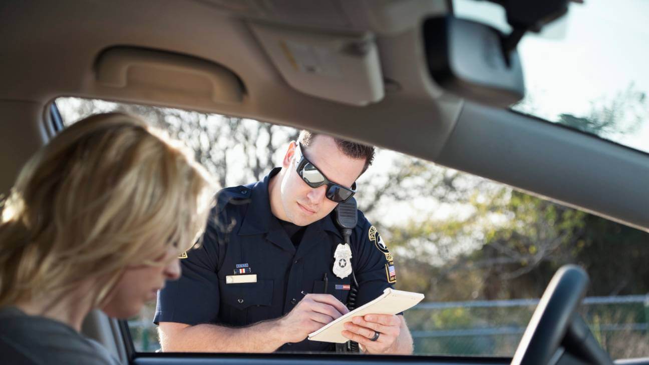 Traffic police officer giving a woman driver a traffic ticket.