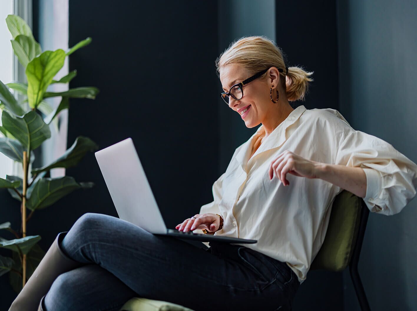 Smiling woman using laptop deligthed to discover LegalShield app.