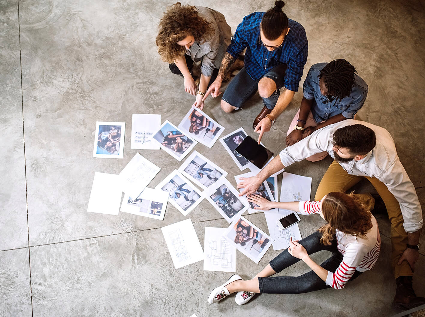 5 employees sorting documents on the floor of an office.