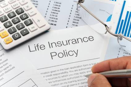 Life Insurance Policy next to a calculator as it is being reviewed.