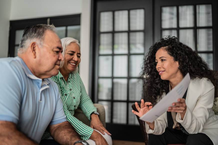 Lawyer explaining a lease vs rental agreement to a mature couple in a living room.