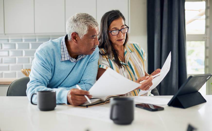 Mature couple reviewing documents to decide what to include in their Will.