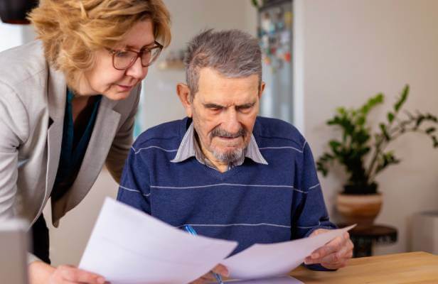 An elderly man reviewing estate planning documents as his LegalShield lawyer helps him understand the legal documents.