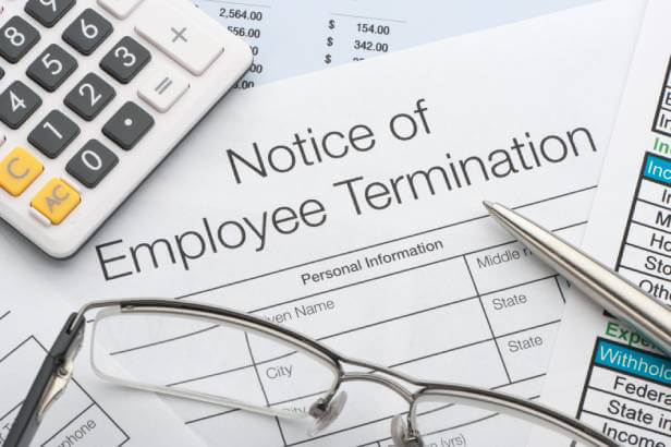 Notice of Employee Termination form next to a calculator, ink pen and eye glasses.