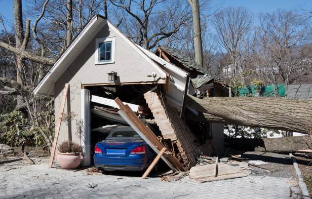 Hurricane damage house garage with damaged vehicle inside.