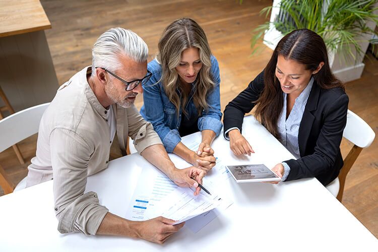 A group of three people sitting around a table reviewing paperwork