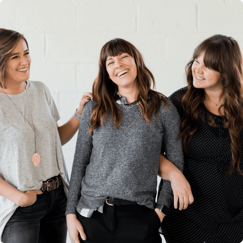 Tres mujeres sonriendo y abrazándose.