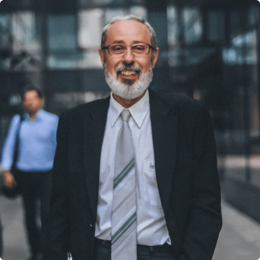 Un sonriente hombre de negocios caminando por la acera de una ciudad.