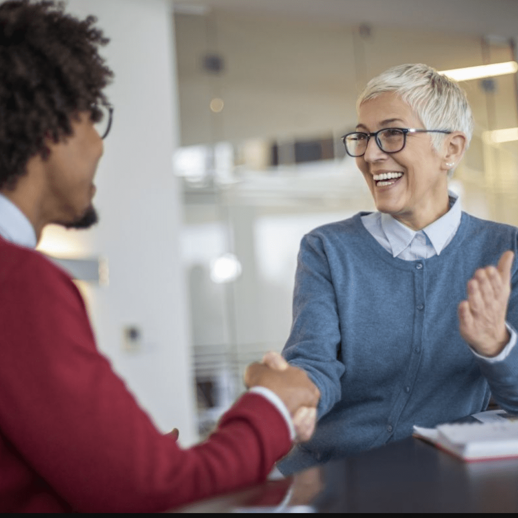 Una empresaria entrevista y da la mano a un posible nuevo empleado.