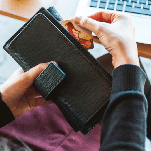 Mujer sacando una tarjeta de crédito MasterCard de su cartera.