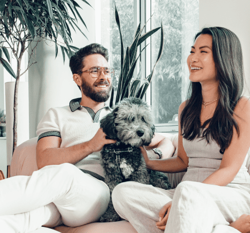 Pareja sentada en el sofá con perro y sonriendo