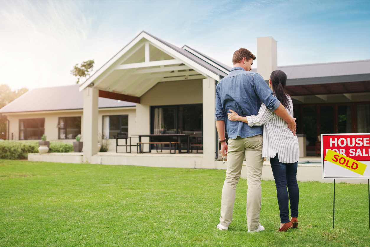 Couple embracing in front yard of recently purchased home